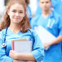 Młoda pielęgniarka w niebieskim uniformie z notatkami i stetoskopem, na tle innych medyków.