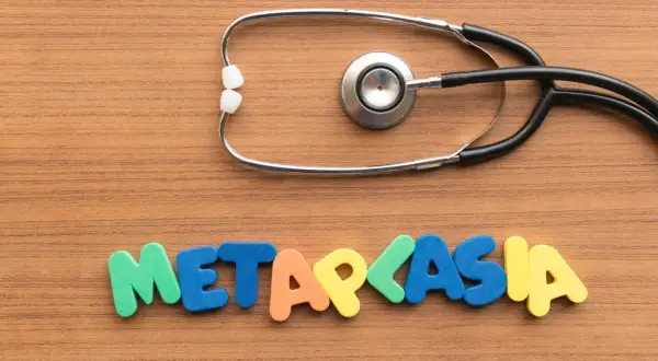 Stetoskop i kolorowe litery układające się w słowo "METAPLASIA" na drewnianym tle.