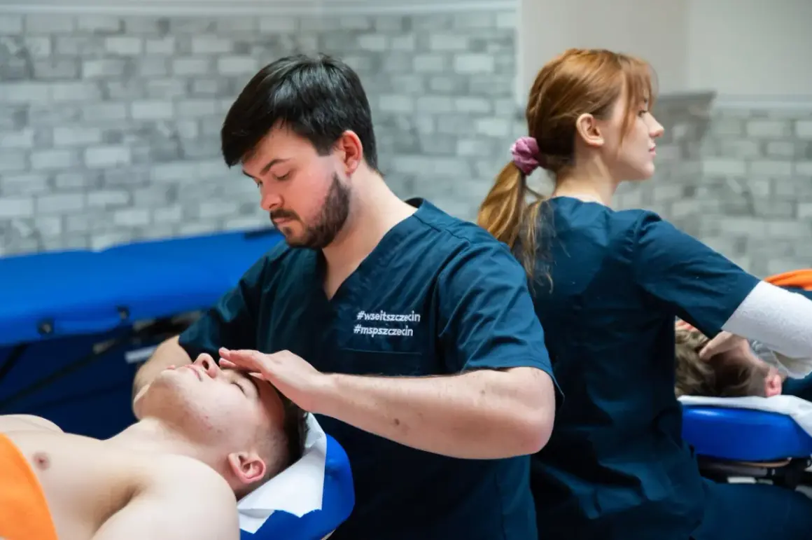 Fizjoterapeuta wykonuje masaż twarzy pacjentowi, w tle druga fizjoterapeutka.