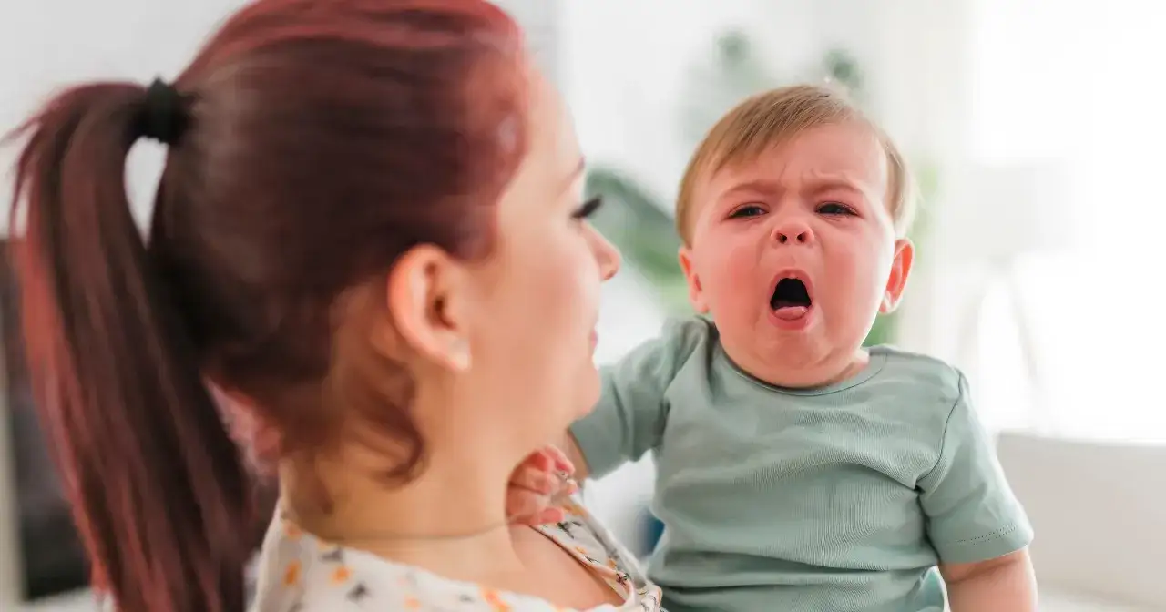 Mama pociesza płaczące dziecko, które może mieć objawy RSV.