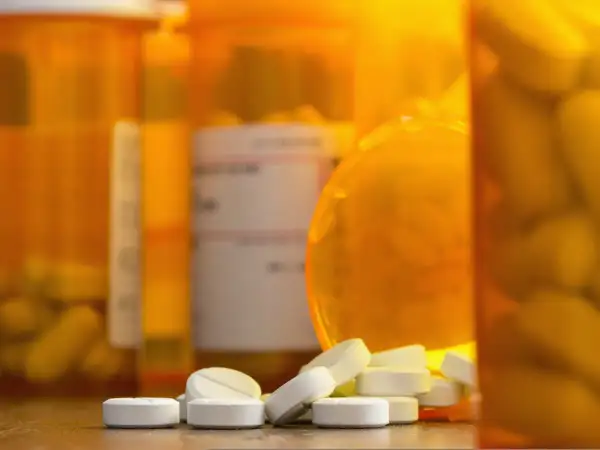 Białe tabletki rozsypane przed pomarańczowymi buteleczkami. Czy to oxycodone, co to za lek?