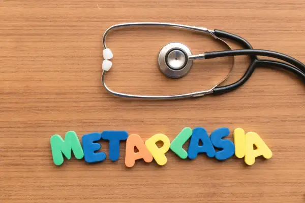 Stetoskop i kolorowe litery układające się w słowo "METAPLASIA" na drewnianym tle.