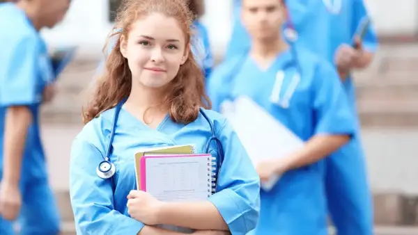 Młoda pielęgniarka w niebieskim uniformie z notatkami i stetoskopem, na tle innych medyków.