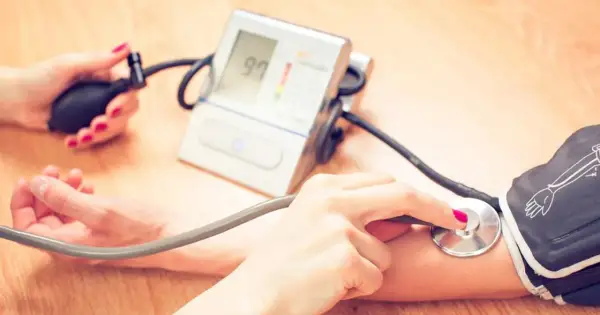 Dwie osoby mierzą ciśnienie. Jedna ręka trzyma pompkę, druga stetoskop. Na ekranie ciśnieniomierza widnieje wynik 97. To ważne, by kontrolować ciśnienie, zwłaszcza jeśli przyjmujesz leki, np. co Valsacor.